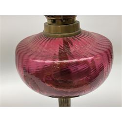 Victorian table standing oil lamp, brass fittings, cranberry glass reservoir, brass column on black enamelled ceramic base, with a frosted glass shade and clear glass chimney, H68cm