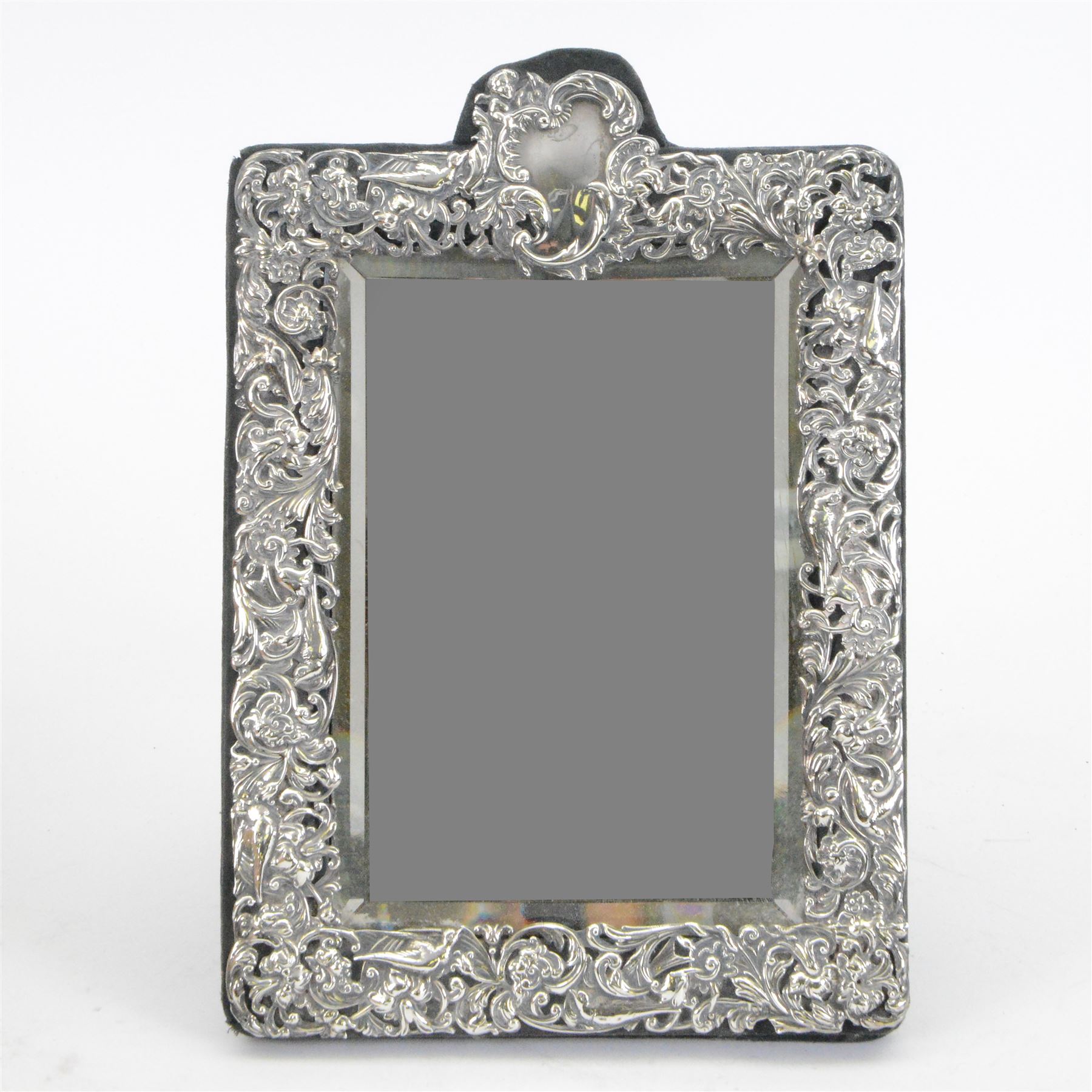 Edwardian silver mounted dressing table mirror, the bevelled mirror plate with silver surround embossed with flowers, C scrolls, putti and birds, with velvet easel support verso, hallmarked London 1903, maker's mark WC, probably for William Comyns & Sons, H33cm