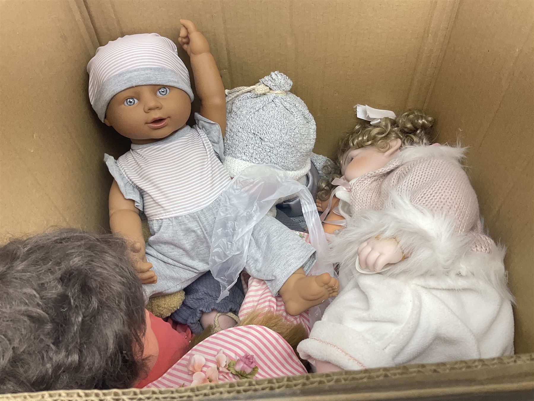 Two decorative wicker dolls prams, one with lace parasol,  and eleven dolls, including Leonardo Collection porcelain dolls, tallest pram including parasol H105cm