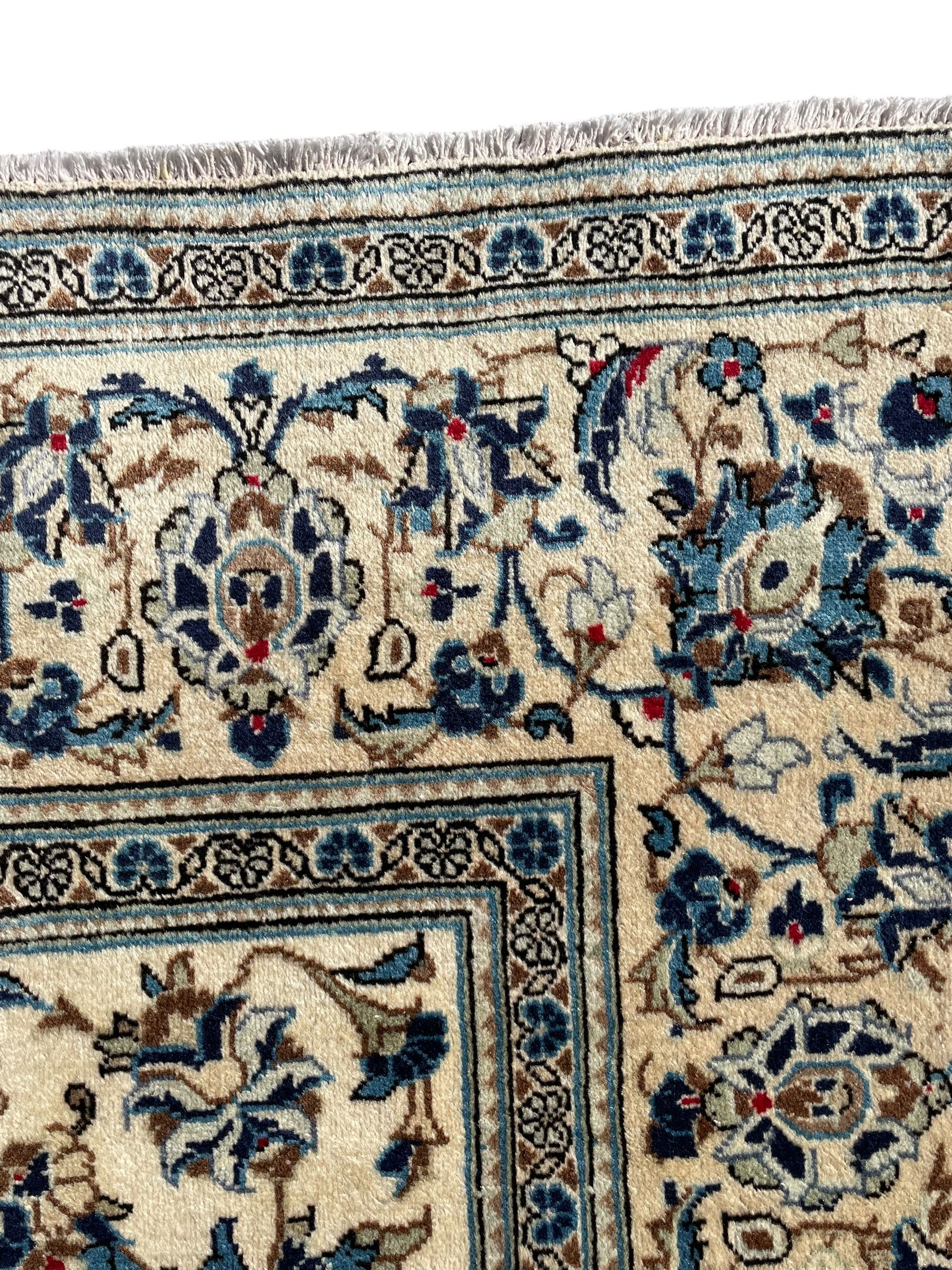 Persian Kashan ivory ground rug, the field decorated with trailing branches with leaves and palmettes, similar scrolling border, within floral pattern guard stripes 