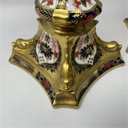 Pair of modern Royal Crown Derby Old Imari 1128 pattern candlesticks, each with shaped drip tray affixed to squat socket, upon spreading stem and canted square base with gilt dolphin edges, with printed marks beneath including Roman numeral year cypher for 2003, H26.5cm, with original boxes