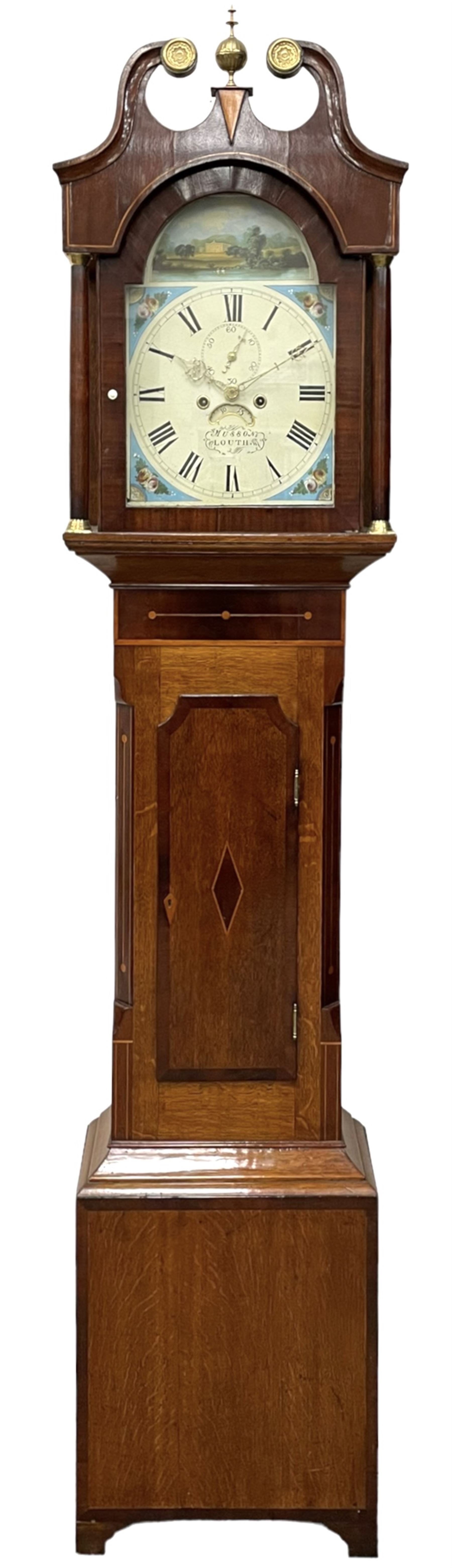 Musson of Louth - mid-19th century oak and mahogany 8-day longcase clock, with a swan’s neck pediment and ball and spire brass finial, break arch hood door flanked by reeded pilasters with brass capitals, canted angled trunk, flat topped door with concave corners, rectangular plinth on bracket feet, fully painted break arch dial with Roman numerals and minute track, subsidiary seconds dial and calendar aperture, matching stamped brass hands, eight day rack striking movement with anchor escapement. With weights and pendulum.
H206 W44 D23
Balthazar Musson from Baden (Germany) is recorded as working in Louth from 1835, naturalised 1861-8. Succeeded by his son, George Balthazar 1872-1920. 
