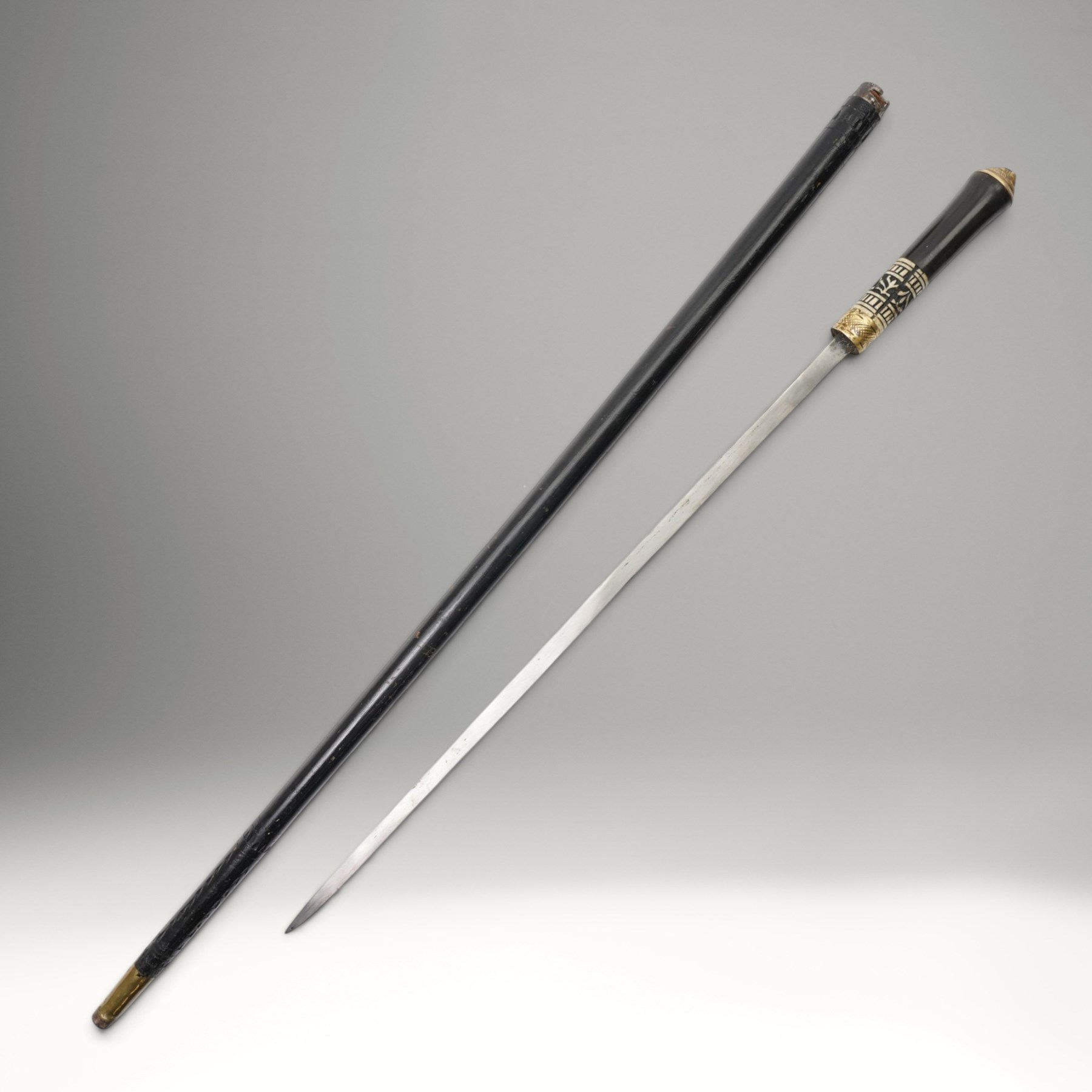 Early 20th century Indian concealed sword-stick, the black wooden scabbard and grip with carved bone collar, engraved brass band, and brass pommel in the form of a tigers head, W92cm