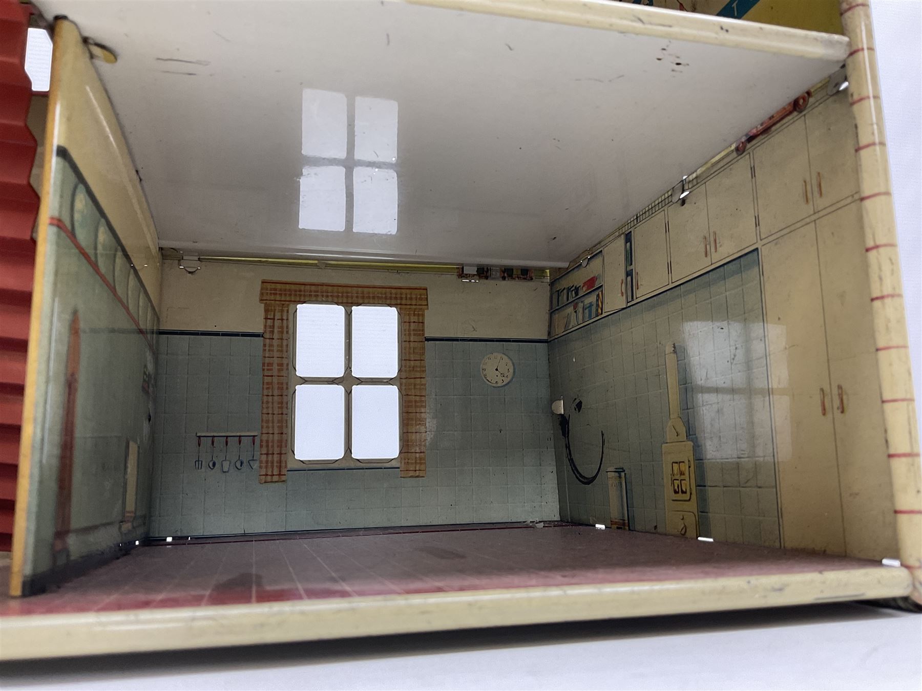 Mid-20th century Mettoy tin-plate double-fronted two-storey doll's house, the front elevation with five unglazed windows flanked by green shutters, central opening door, open back giving access to five rooms together with an attached garage, 60cm wide