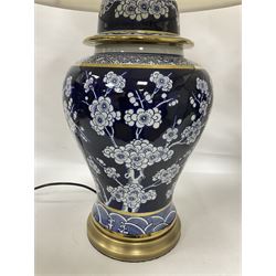 Pair of blue and white table lamps, each of baluster form, decorated with prunus blossom, within stylised borders, raised upon circular gilt base, excluding fittings H48cm