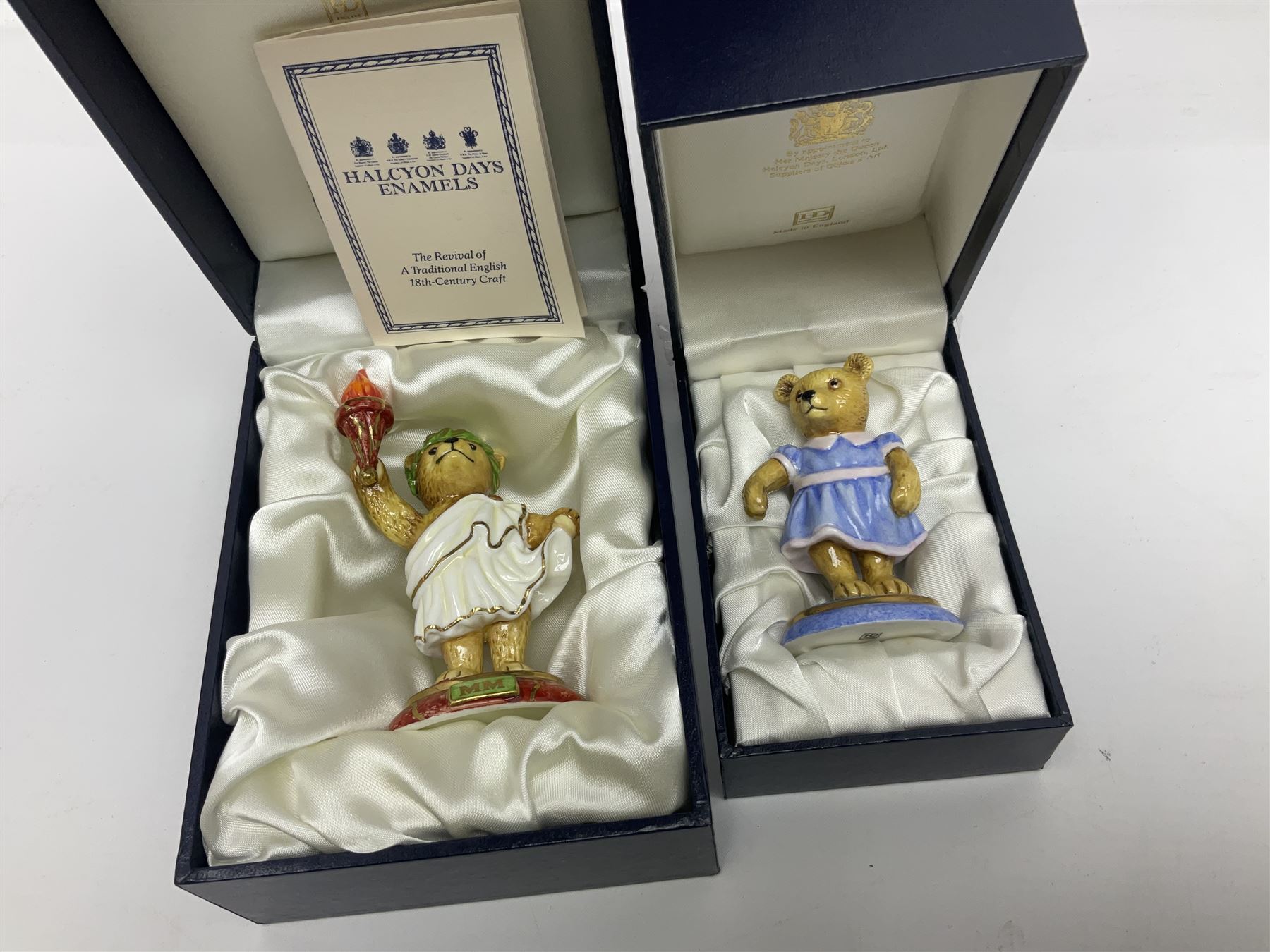 Eight Halcyon Days Teddy Bear of the Year figures, from 1993 to 2000, including one example modelled as a bear in Greek dress carrying a torch, one example modelled as a schoolboy and one example in a blue dress, all boxed 