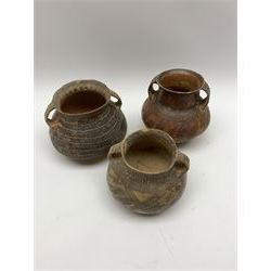 Three Chinese Neolithic pottery vessels, each with twin loop handles to the shoulder and painted geometric banded decoration to the body, all bearing labels for Eskenazi London, tallest H14cm