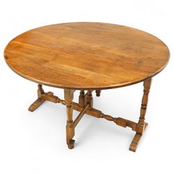 Early 20th century oak gate-leg low table, the oval top on twin gates, supported by turned...
