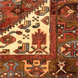 North West Persian Zanjan hand-knotted rug, madder-red field with a central stepped lozenge medallion enclosing stylized geometric floral motifs in indigo, ivory, and brown, angular spandrels filled with tribal devices and framed by a series of geometric borders with latch-hook rosette and leaf motifs, with cotton fringe ends  