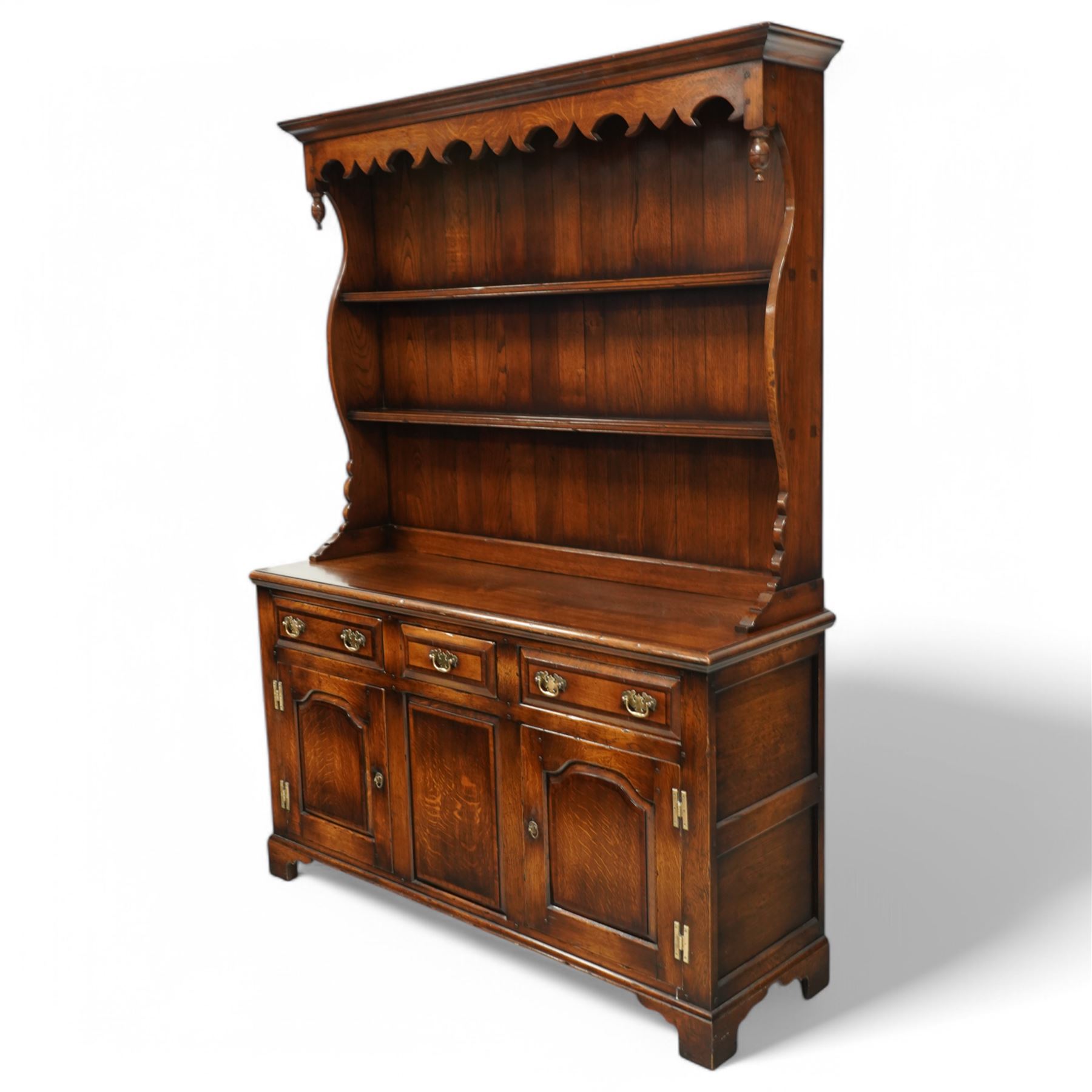 Gostins of Liverpool - Georgian design oak dresser, the two-tier rack with moulded cornice over shaped frieze and end supports, the dresser base with moulded rectangular top over tree drawers and two cupboards, panelled sides, on bracket feet