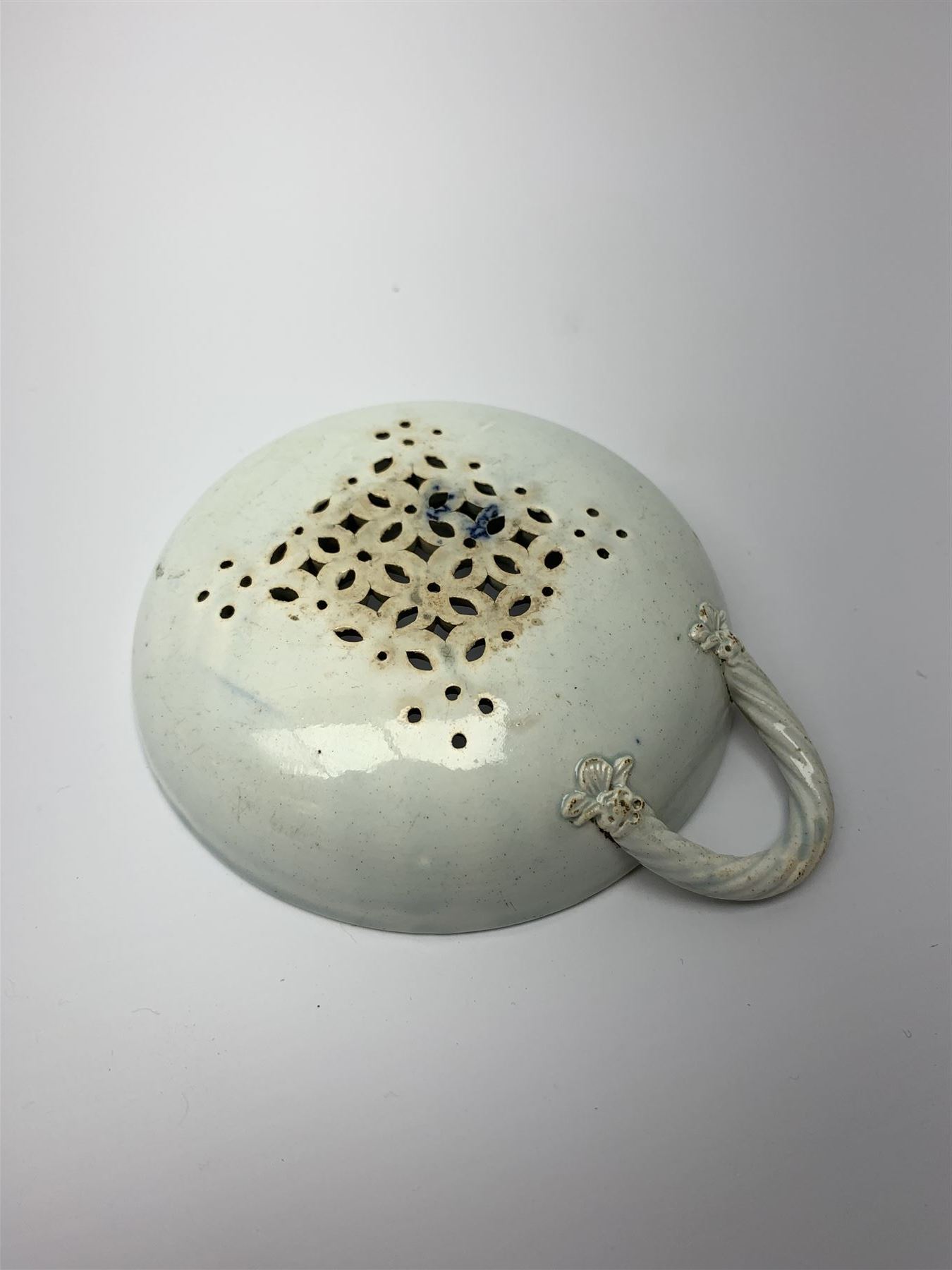 Late 18th/early 19th century Leeds Pottery egg drainer, the pierced bowl of circular form decorated with blue transfer printed floral spray and floral border, the twisted handle with foliate mounts, bowl D9cm