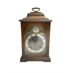 Imperial - English 1950s walnut and mahogany 8-day veneered mantle clock in an18th century-style case, with an inverted bell top and handle, break arch brass dial with a matted centre, silvered chapter ring with roman numerals and trefoil steel hands, cast spandrels and silvered Tempus Fugit boss to the arch, with a rack striking movement striking the hours and half hours on a gong. With pendulum and key.