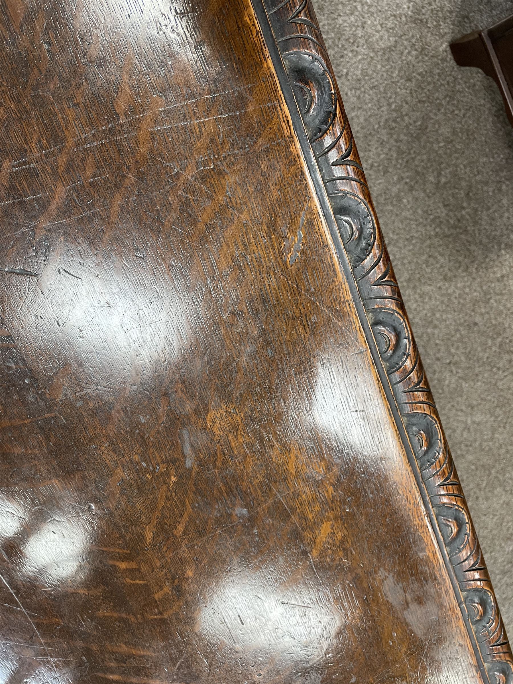 Large 19th century carved oak library table, the rectangular top with lunette carved edge over cartouche panelled and carved  scroll frieze, the central tapering rectangular support relief carved with masks and garlands, on four carved seated lion supports at each corner, on flat angular stretcher with recessed castors stamped ‘Bartholomew & Fletcher, London’