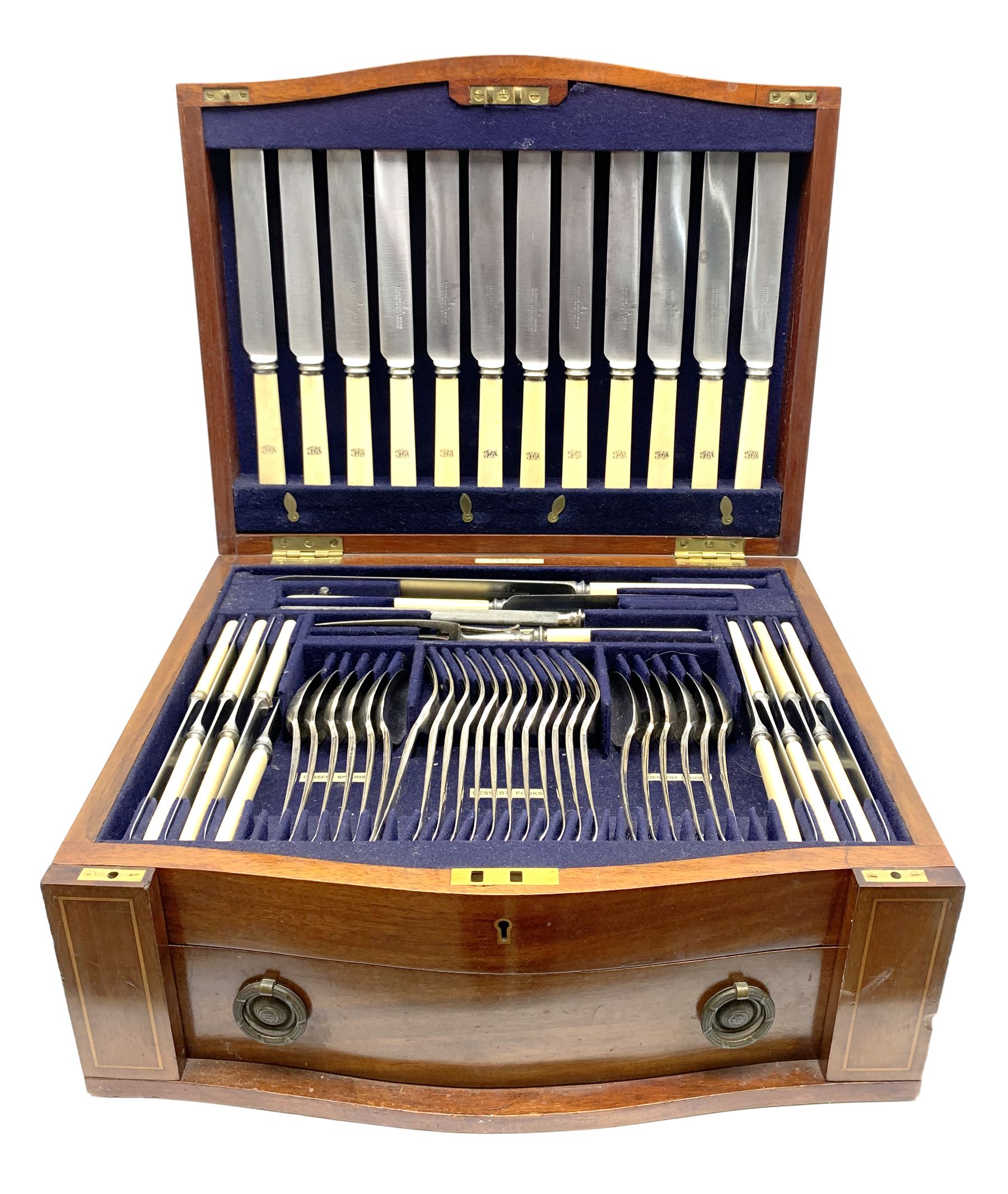 Late 19th/early 20th century composite canteen of silver flatware, contained within an early 20th century mahogany serpentine fronted case with twin drop carry handles, and hinged cover with boxwood stringing and central inlaid shell motif, above a single drawer with twin ring handles and Wellington style locking system, the cover and drawer opening to reveal plaque for Spink & Sons Ltd London, and fitted interior containing ivory handled knives, ivory handled carving set, and silver Hanoverian and Old English pattern cutlery, each with engraved monogram to terminal, hallmarked London, makers Spink & Son (John Marshall Spink), Goldsmiths & Silversmiths Co, and Chawner & Co (George William Adams), various dates ranging 1880-1923, gross weighable silver 92.59 ozt (2880 grams)