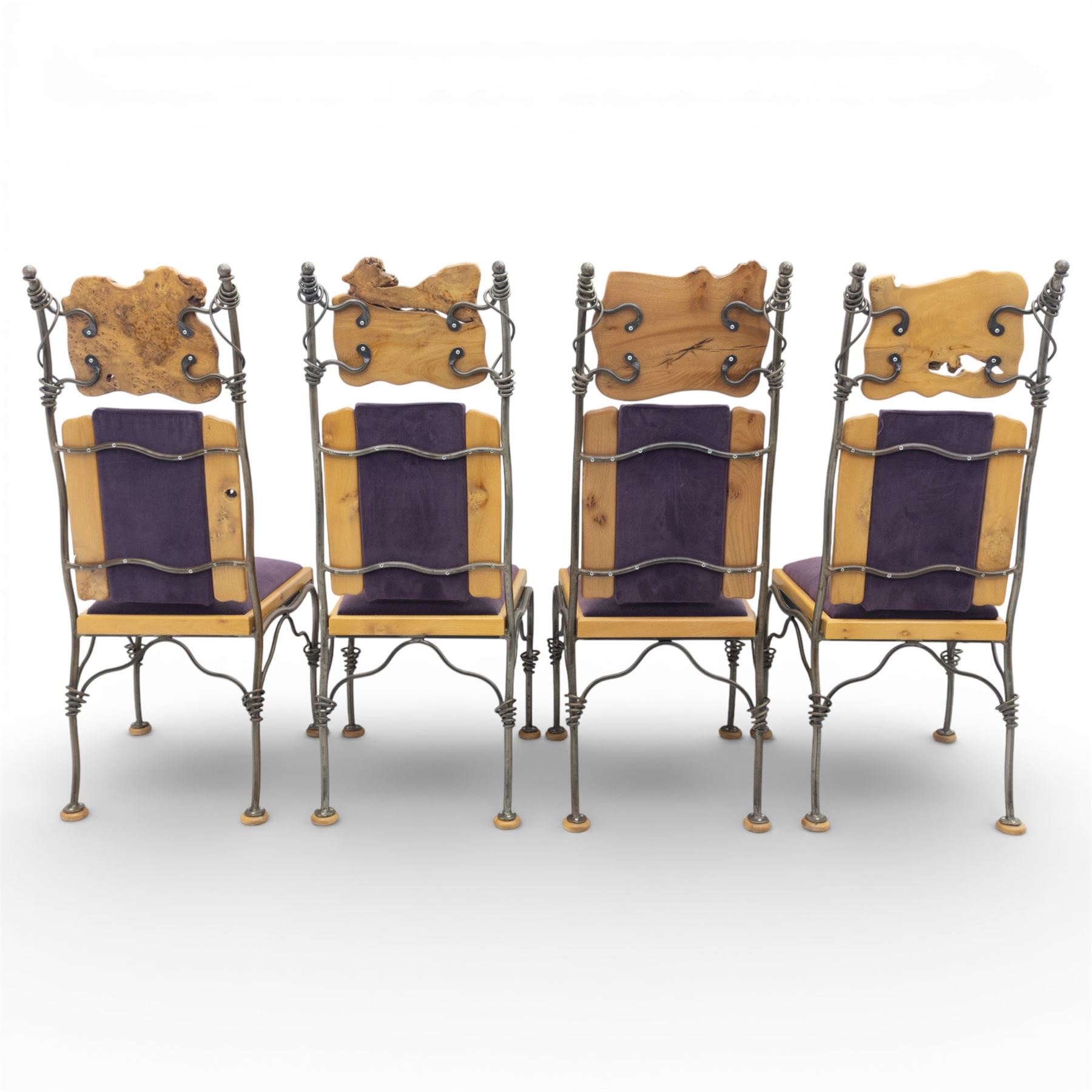 Paul Hodgkiss Designs of Glasgow - contemporary shaped elm dining table with wrought iron base; with set ten (8+2) matching high-back dining chairs, table of organic form above an elaborate wrought iron supports, with central elm stretcher, the chairs with en suite with matching wrought iron work burred elm headrest, purple velour upholstery with drop in seat     

Table: W 102cm, L 243cm, H 74cm
Chairs: W 56cm, D 52cm, H 130cm