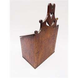 Early 19th century oak candle box, the shaped and pierced raised back above a sloped hinged lid opening to reveal a twin compartmented interior, above a single pull out drawer with ring handle, H38cm W25cm D15cm