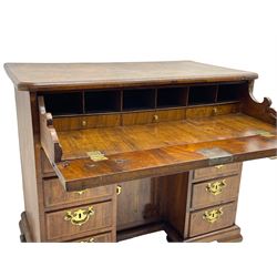 Early 18th century Queen Anne figured walnut kneehole desk with secretaire drawer, moulded and book matched top with walnut band, the top drawer with fall front enclosing small drawers and pigeon holes, fitted with nine drawers and central recessed cupboard, on ogee bracket feet