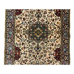 Persian ivory ground rug, central green floral pole medallion within a field decorated by scrolling foliate patterns, the guarded border with repeating palmettes and floral designs