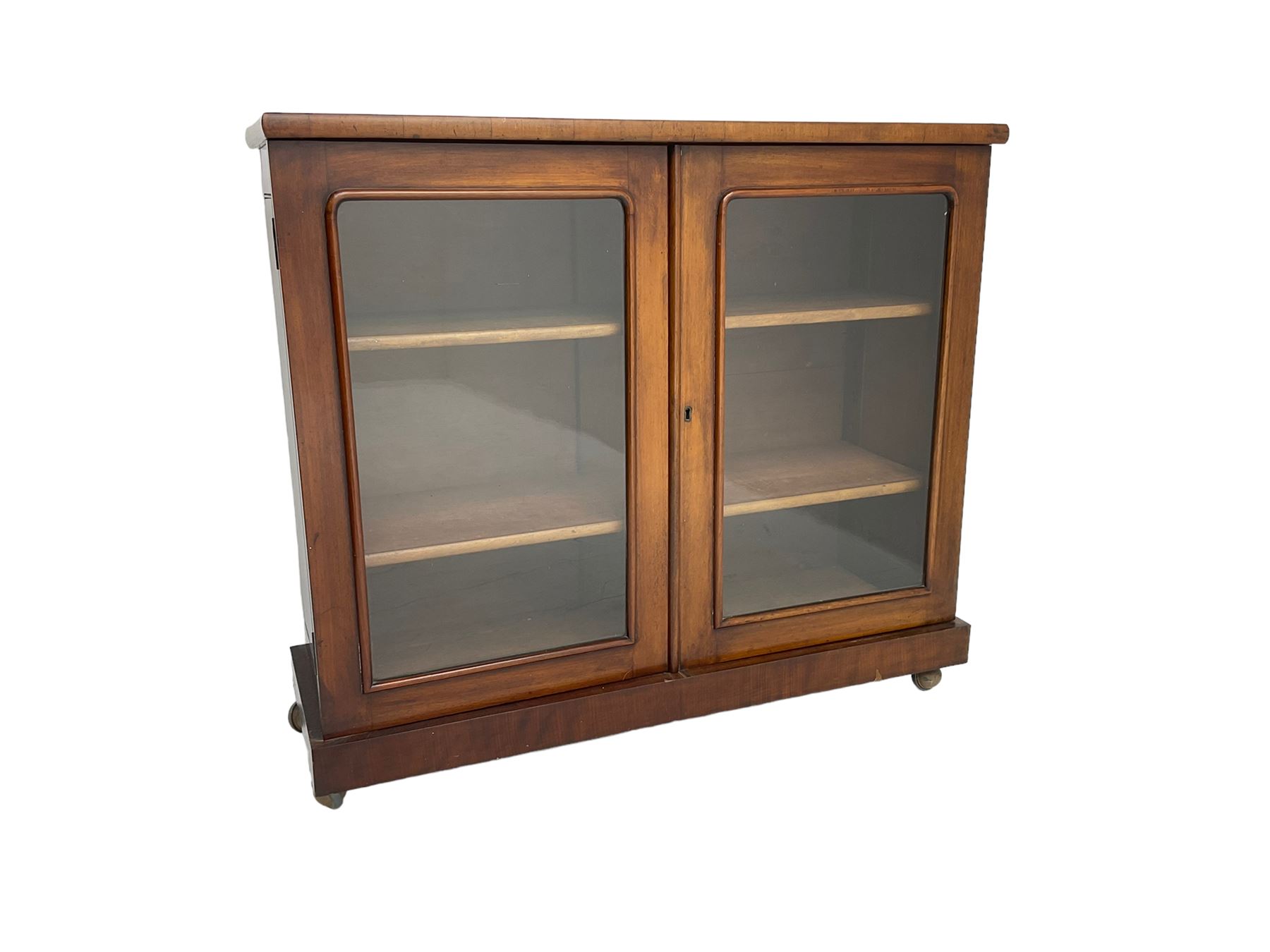 Victorian bookcase, rectangular top over two glazed doors enclosing two shelves, on skirted base