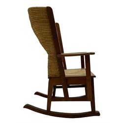 Reynold Eunson (1932–1978) for David Munro Kirkness, Kirkwall, Orkney - oak framed Orkney rocking chair, woven straw curved back, drop-in rush seat, the arm terminals with carved end scroll, on square tapering supports joined by plain stretchers, the front rail inscribed with makers marks