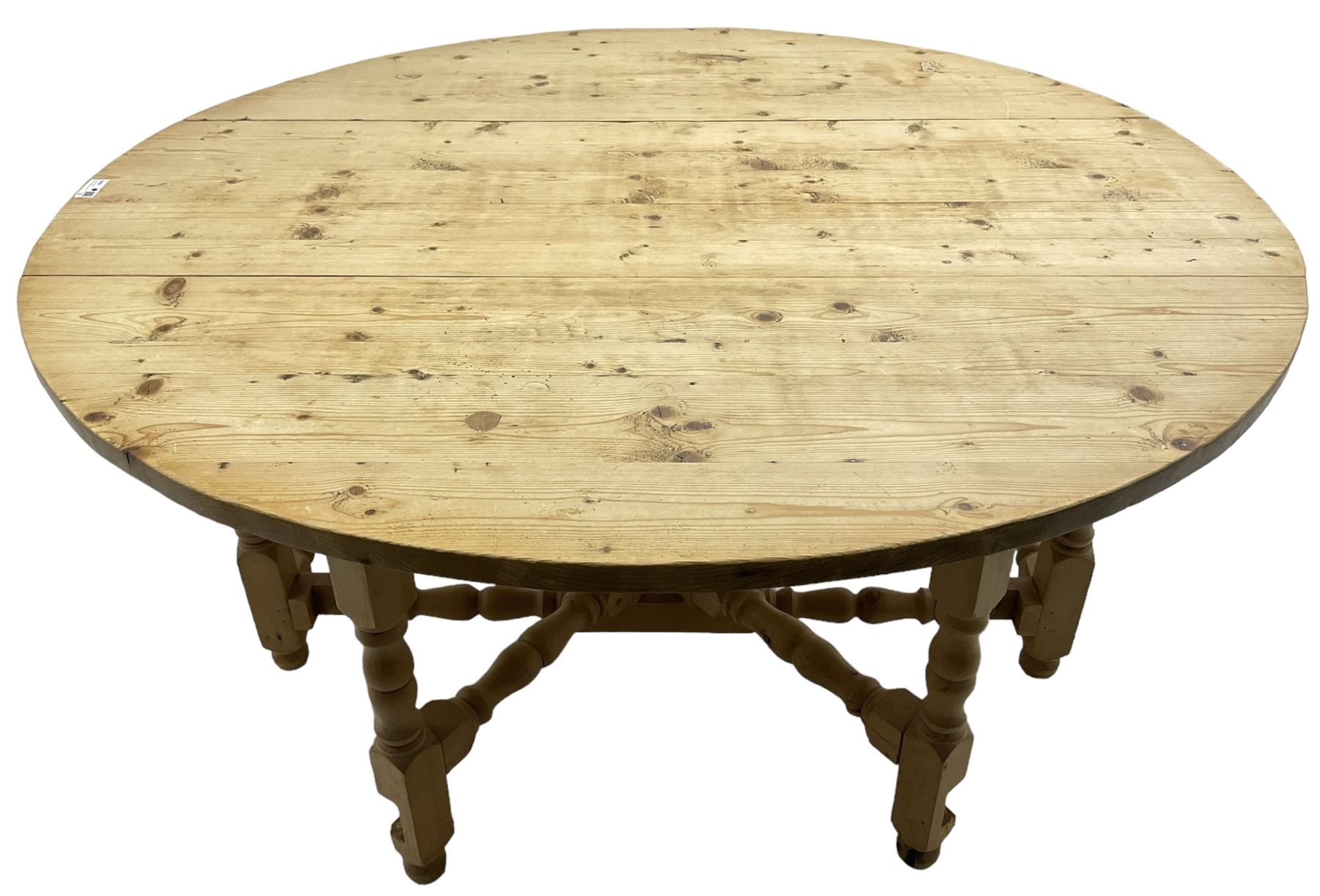 Traditional stripped pine dining table, circular drop-leaf top over double gate-leg action base with turned supports united by turned stretchers