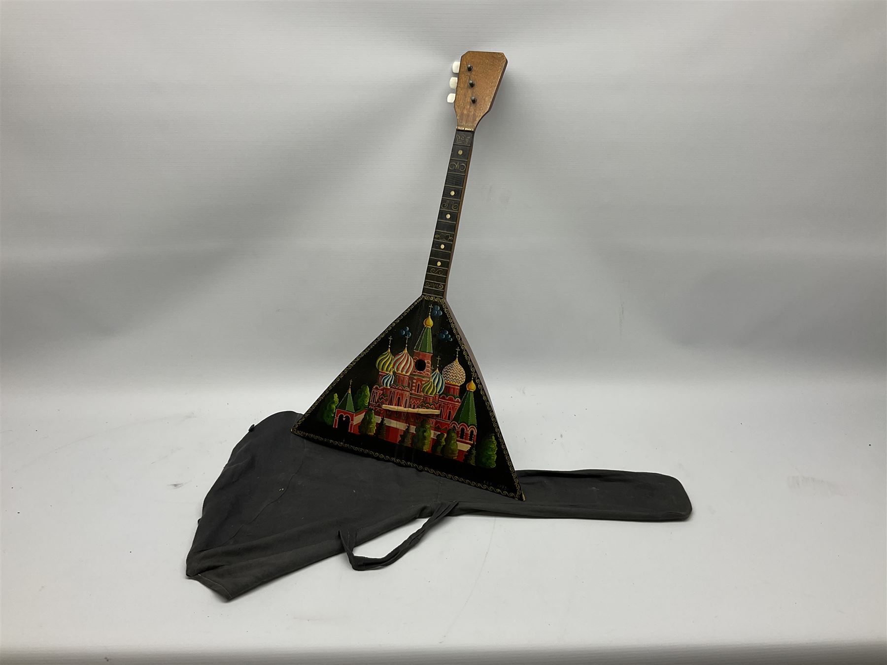 Russian balalaika with six-piece segmented back, the top painted with a scene of Russian onion capped buildings monogrammed K.B.H.1993; bears cyrillic label; L67.5cm; in carrying bag