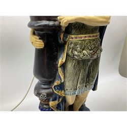 Composite table lamp modelled as a Roman Emperor donning blue robes, upon quatrefoil base modelled with rams heads and winged cherubs, H56cm excl fitting