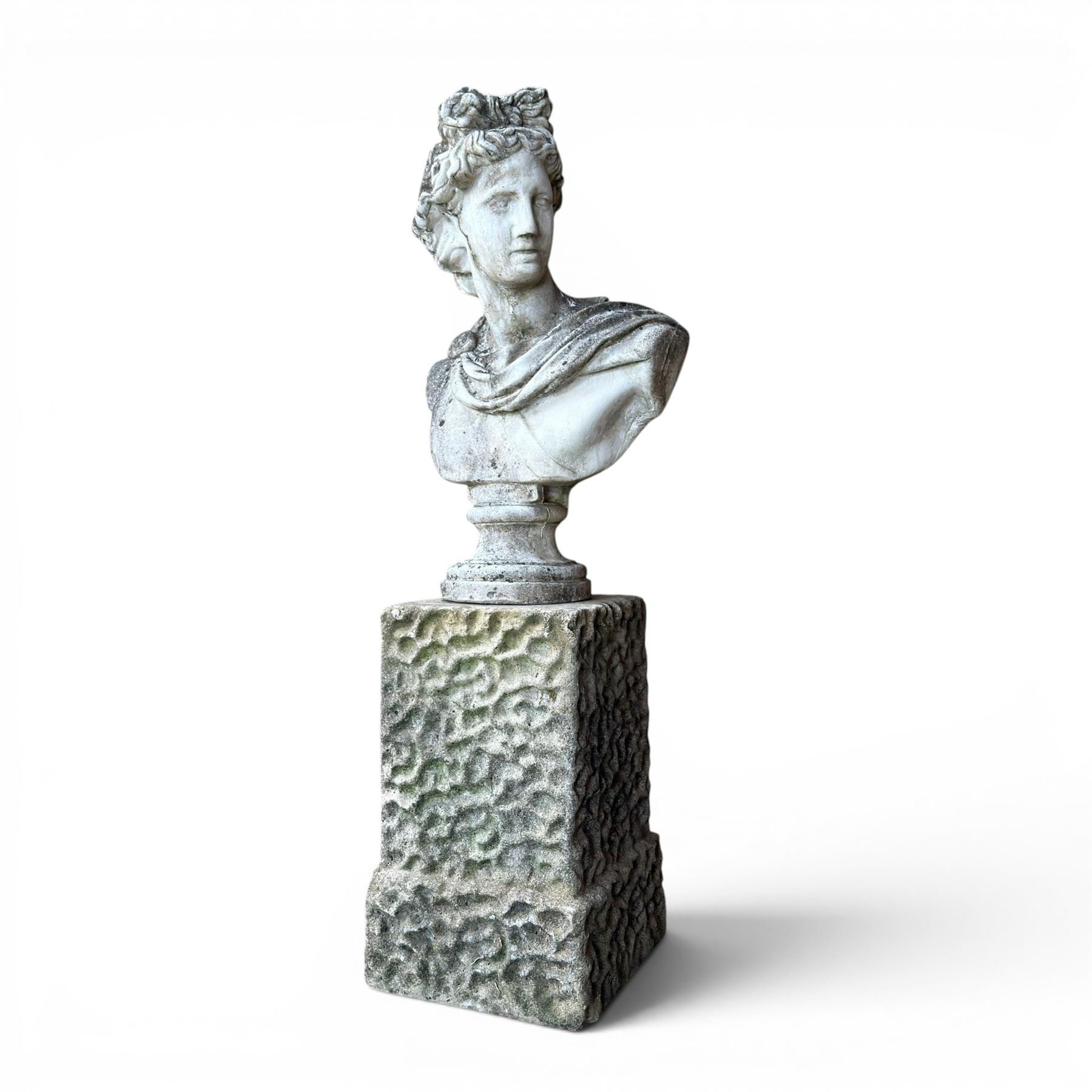 Roman Neoclassical style cast stone bust, weathered finish, raised on textured stone plinth of tapering form