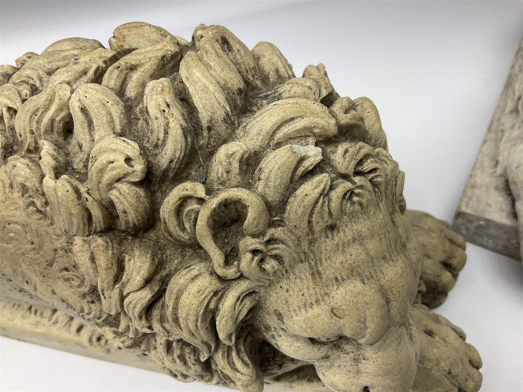 Two early 20th century reconstituted stone Grand Tour or Chatsworth House type lions after Antonio Canova, each modelled in recumbent pose upon a rectangular plinth, signed to plinth Dilettanti, each approximately L31cm