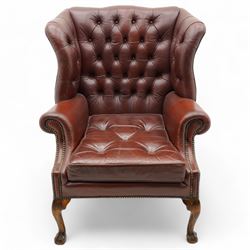 Georgian design leather wingback armchair, deep-buttoned burgundy leather upholstery with rolled arms, studded detail along the edges, raised on cabriole supports terminating in claw and ball feet
