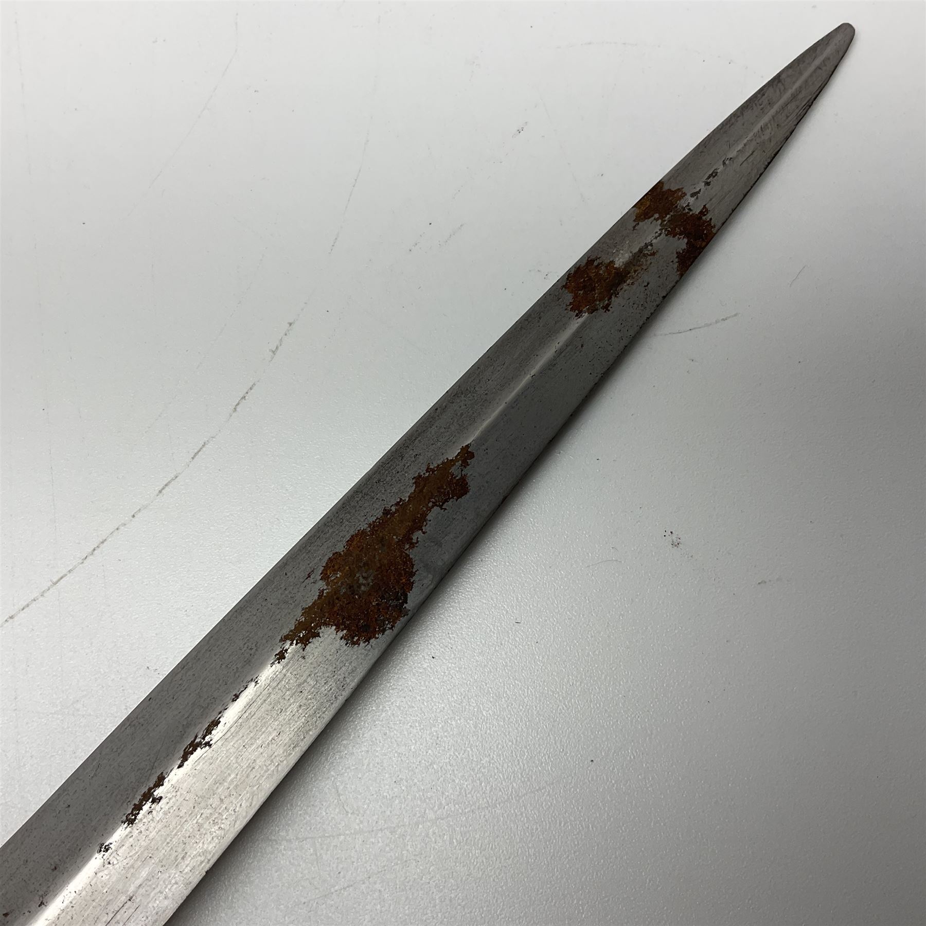 First Pattern Fairburn Sykes ''F-S'' Fighting Knife by Wilkinson Sword Ltd., the 17cm double edge steel blade with raised medial ridge to each side, each side of the ricasso with a recessed panel, one side with maker's name, the opposing side etched THE F~S FIGHTING KNIFE, with nickel plated brass recurving crossguard and diamond cut grip; in leather scabbard with metal chape