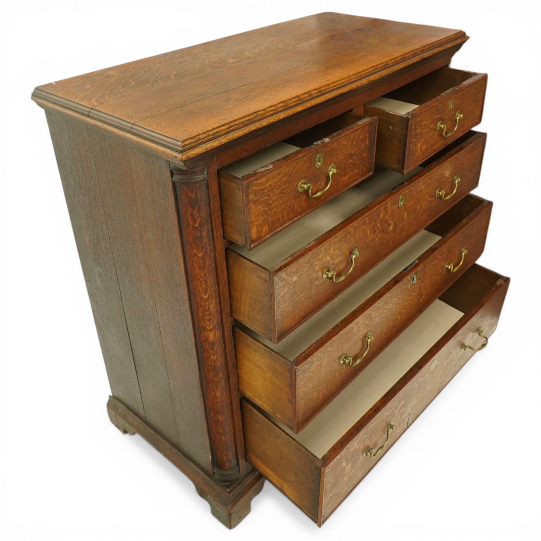 Georgian oak chest of drawers, fitted with two short over three long drawers, with brass swing handles and escutcheons, flanked by quarter turned pilasters, raised on shaped bracket feet