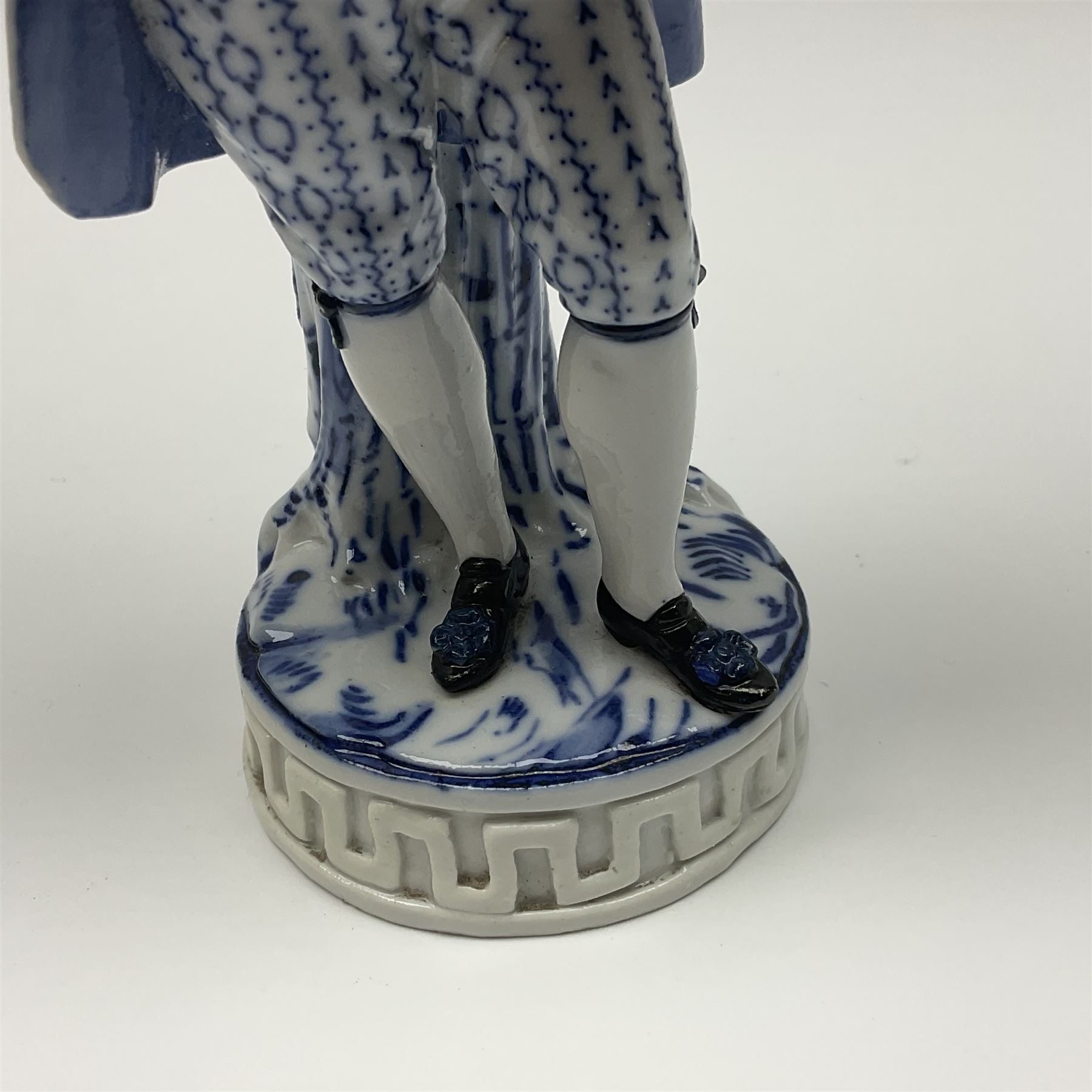 Meissen blue and white figure, modelled as a gentleman holding a hat of flowers, raised upon Greek key design base, with blue crossed swords and impressed C 73 and 149 marks beneath, H18cm