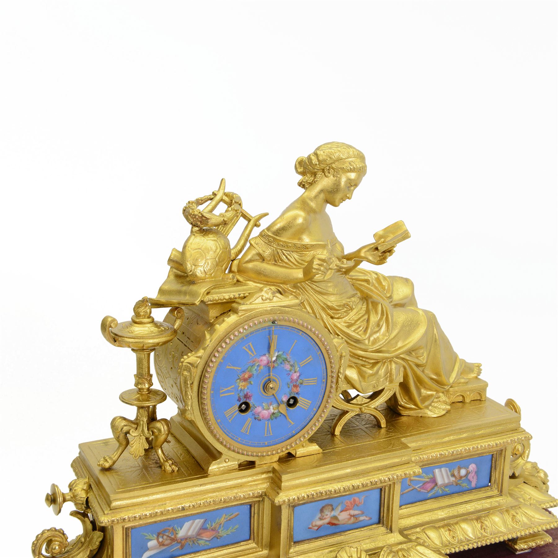 French- Napoleon III porcelain inset 8-day figural clock in a gilt case c1870, drum housed movement resting on a rectangular plinth with light blue porcelain panels each painted with different classical images and depictions from antiquity, conforming dial with a garland of flowers to the centre, gilt Roman numerals, minute track and brass spade hands, with a seated figure of a classical maiden reading a book, mounted on a matching gesso base with a velvet padded top, Parisian countwheel striking twin train movement, striking the hours and half hours on a bell. With a contemporary ebonised base and oval glass dome. With pendulum.
