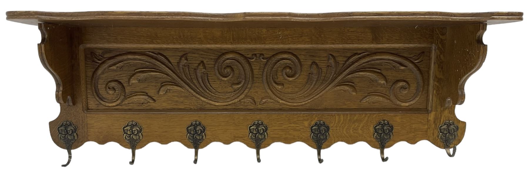 Oak wall hanging coat rack, shape lintel over panelled back carved with foliate S-scrolls, fitted with seven hooks
