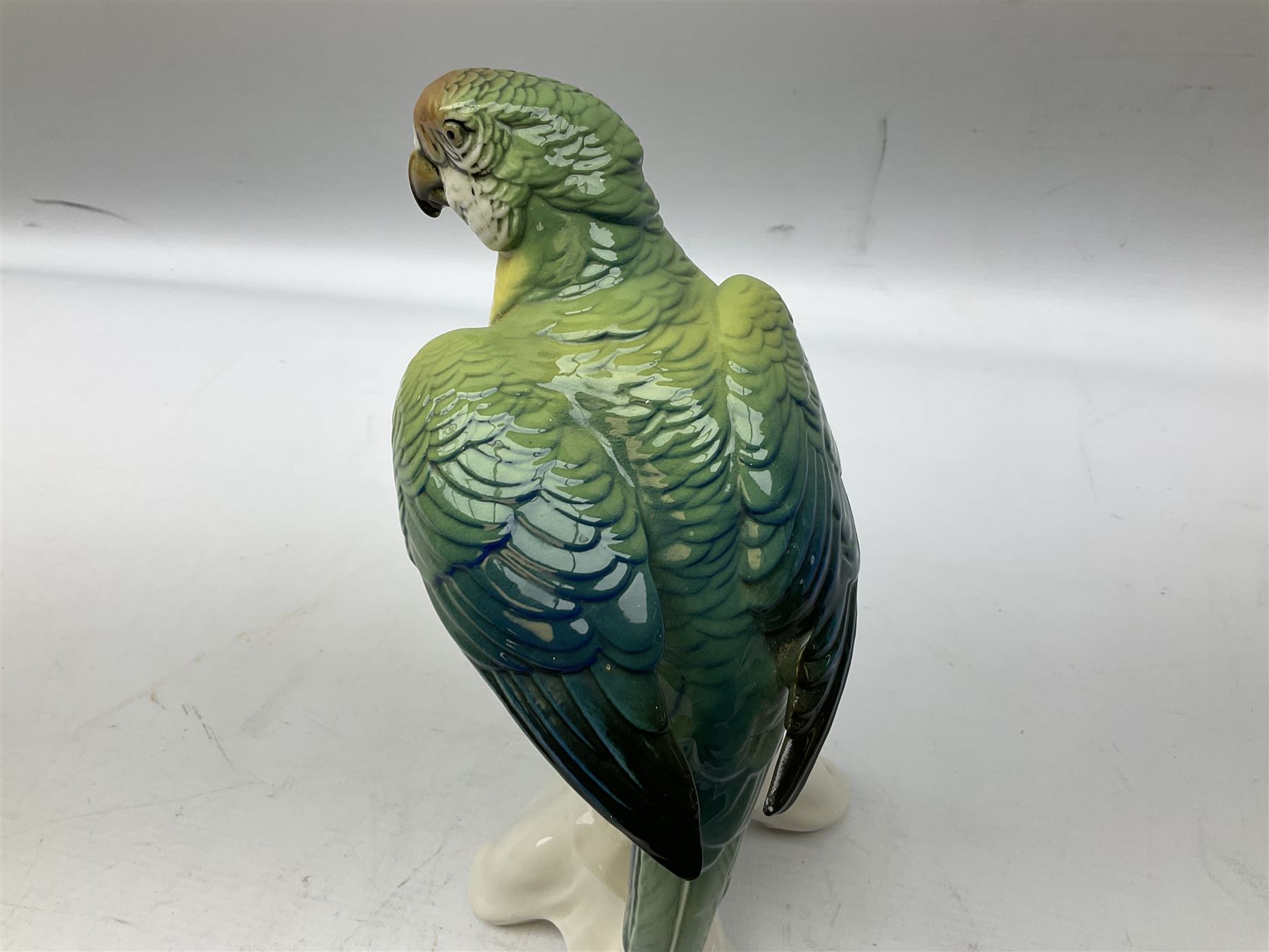 Karl Ens porcelain figure of a parrot, modelled with yellow breast, blue back and wings and green tail, perched upon on a blossoming branch, with blue printed factory mark beneath, H24.5cm