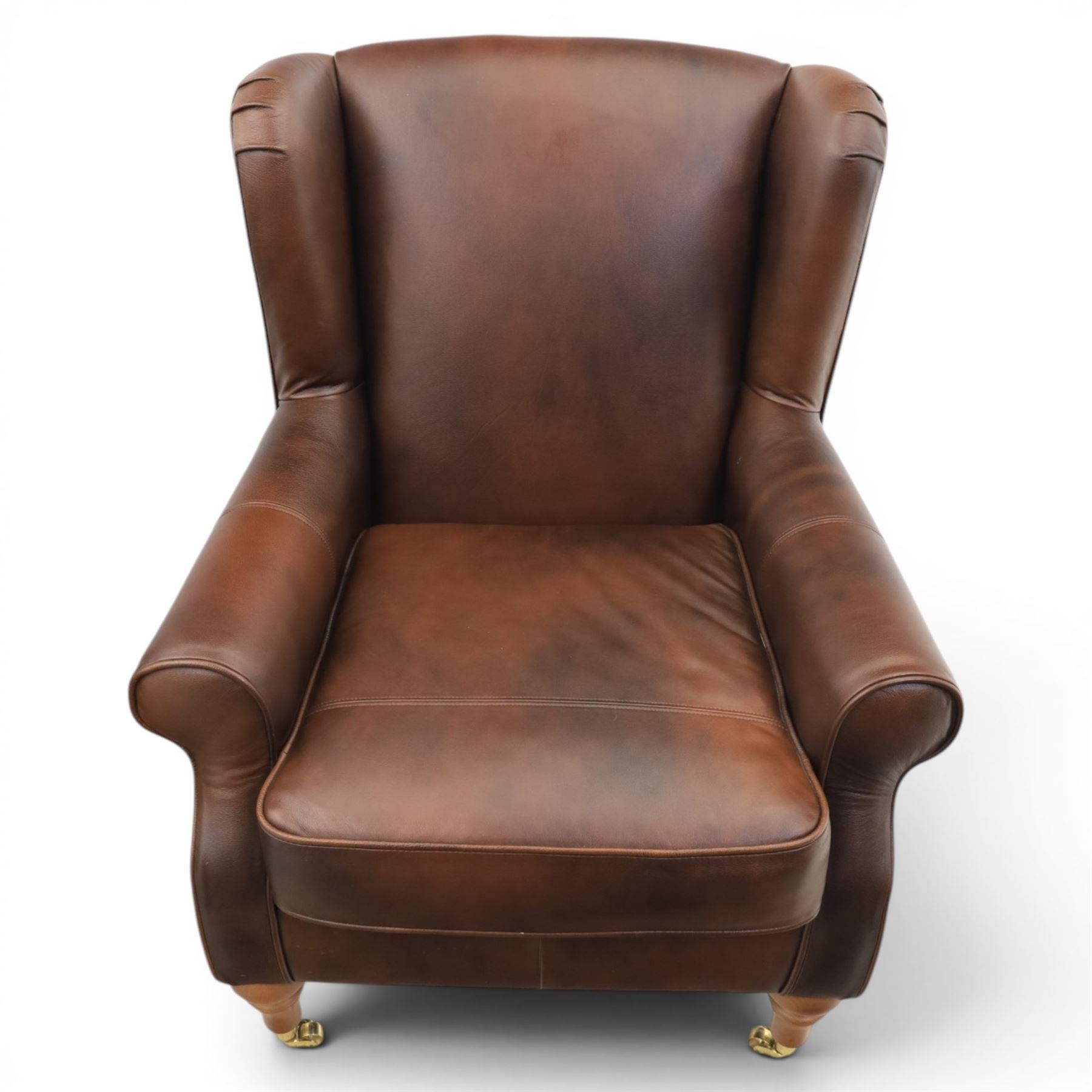 Marks & Spencer - Pair of brown leather wing back chairs, raised on light stained supports with castors