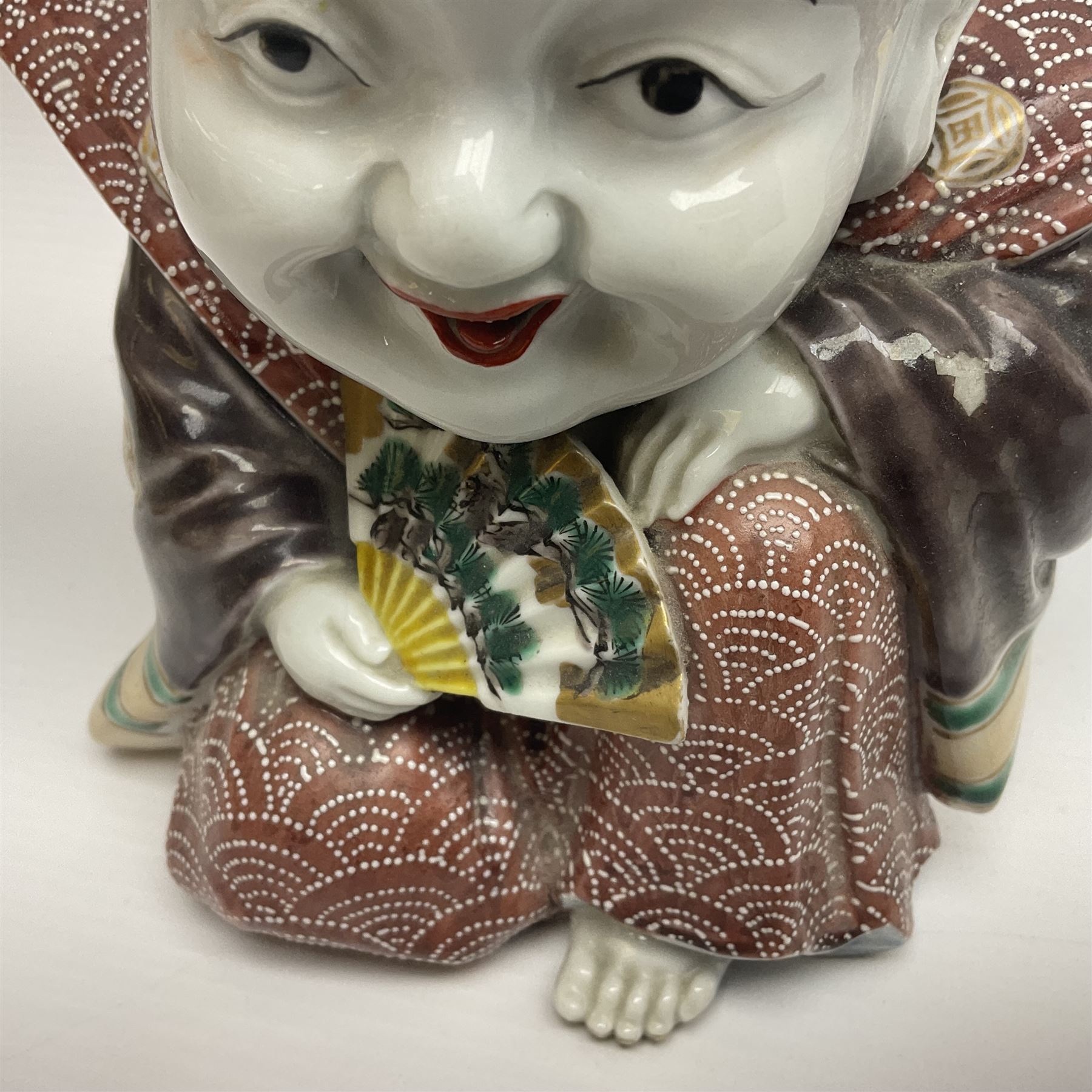 Japanese Fukusuke good fortune figure, modelled as a kneeling male figure holding a fan, dressed in traditional Samurai robes, H15.5cm