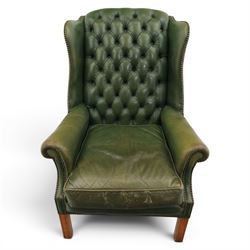 20th century green leather wingback button backed armchair, brass studded trim, with scrolled arms raised on oak supports