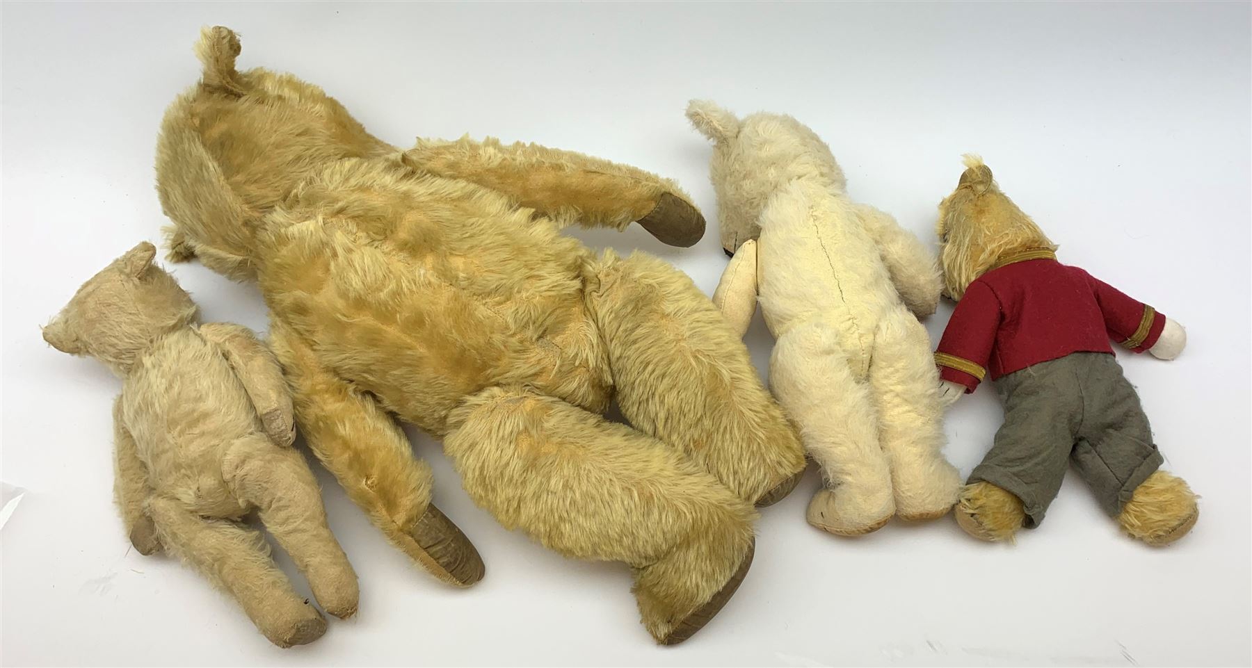 Four Chiltern teddy bears 1930s-50s, including white one with revolving head, glass type eyes, vertically stitched nose and mouth and jointed limbs with felt paw pads H16.5