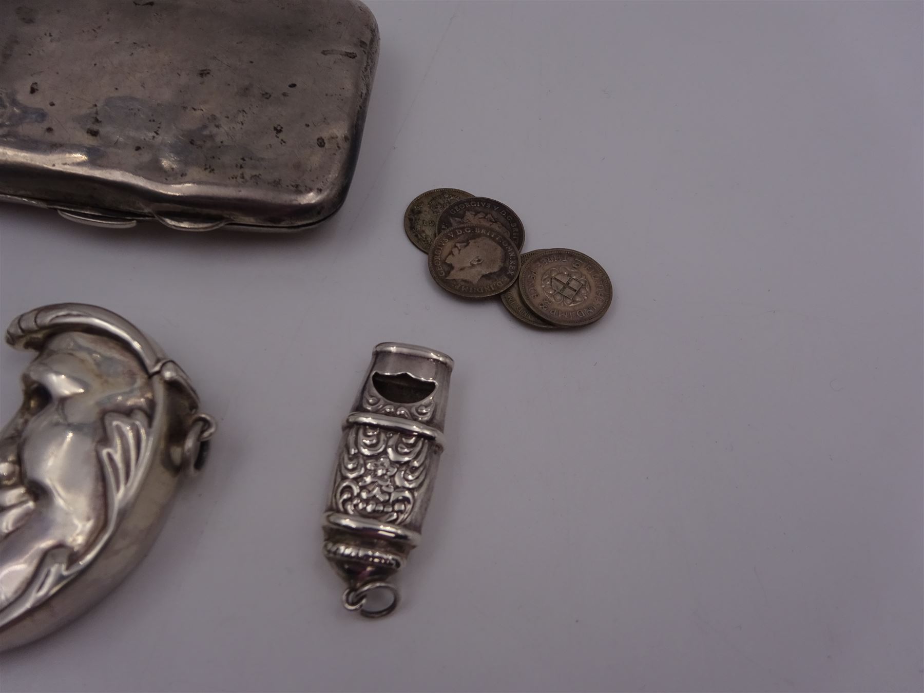 Group of novelty silver items, comprising man in the moon vesta case, perfume pendant and a whistle, unmarked but test silver, together with a mother of pearl handled silver fruit knife, silver cigarette case, both hallmarked and a small quantity of silver threepences
