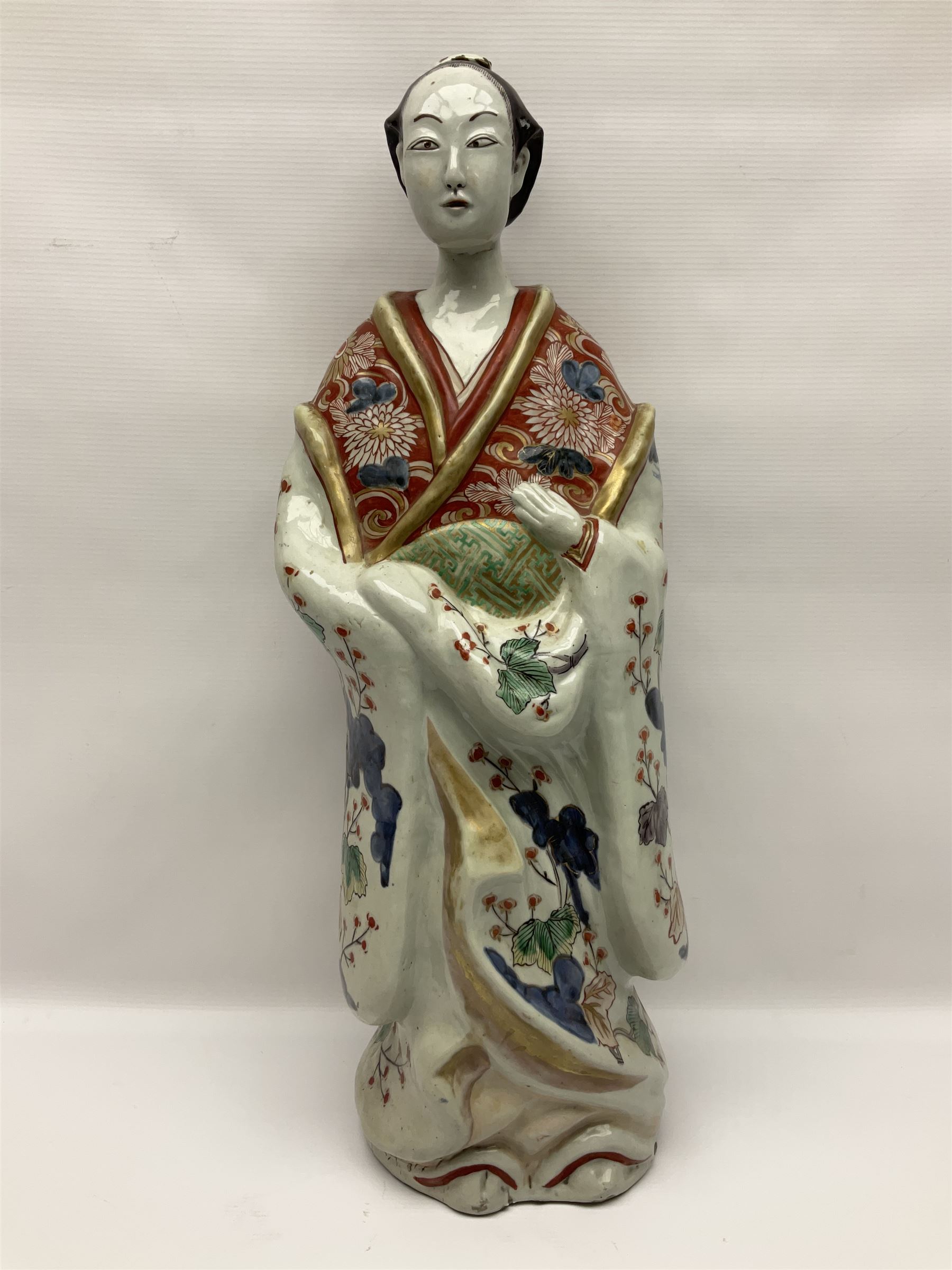 Large Japanese Imari porcelain figure, modelled as a Bijin, wearing a long kimono decorated with apple blossom and leafy branches on a white ground, with gilt detailing, possibly Edo period, H63cm