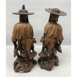 Pair of Japanese carved wooden figures, modelled as merchants in traditional dress, upon pierced naturalistic bases, tallest H39cm