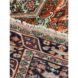 North West Persian Bidjar rug, orange peach ground extended field on indigo ground, decorated with floral Herati motifs, repeating waved border decorated with stylised plant motifs