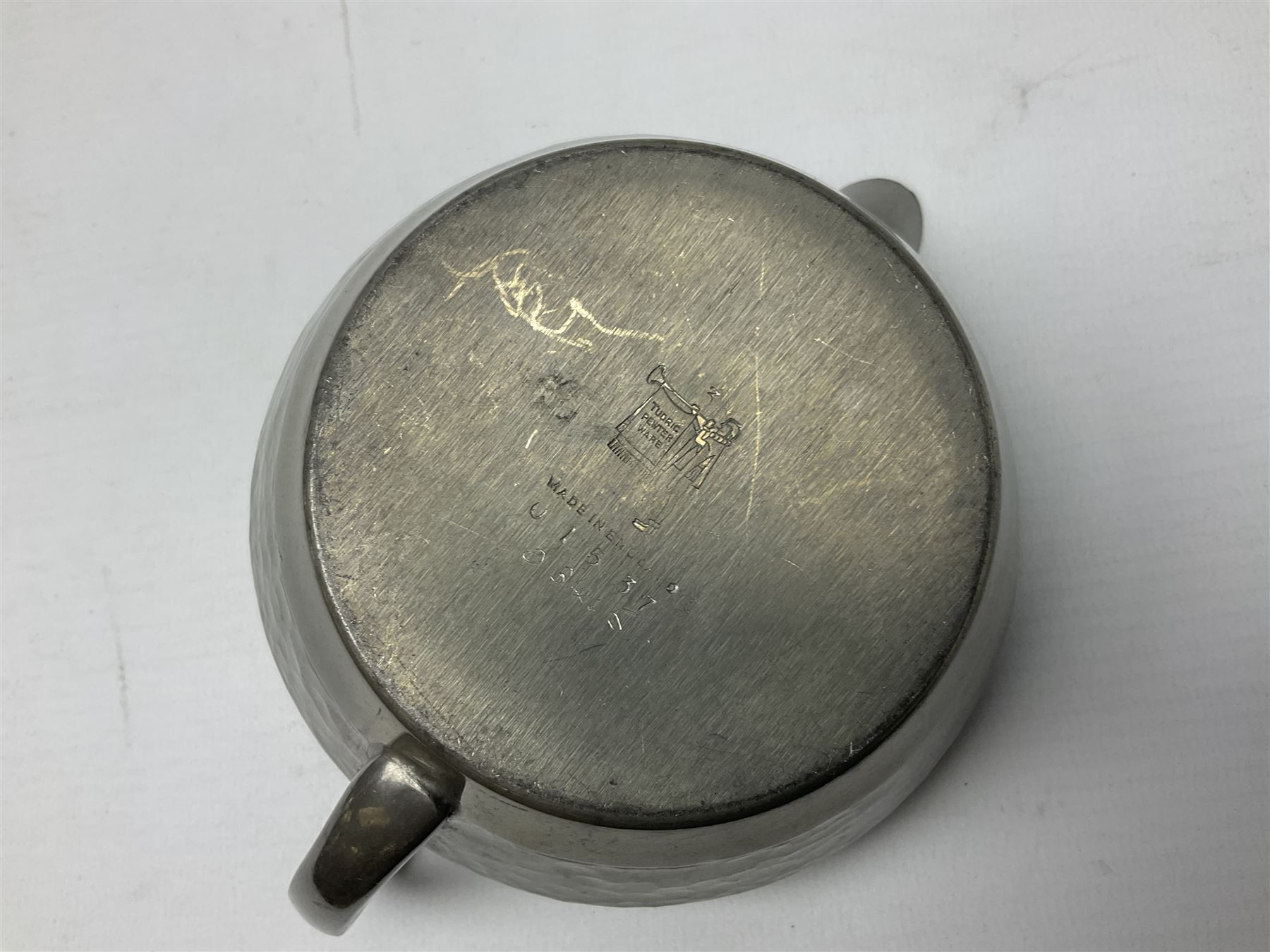 Liberty & Co Tudric pewter three piece tea service, comprising teapot with woven reed handle, twin handled open sucrier, and milk jug, each of squat form with planished finish, each impressed beneath Tudric Pewter Ware 01537 Made in England, together with a matched unmarked tray