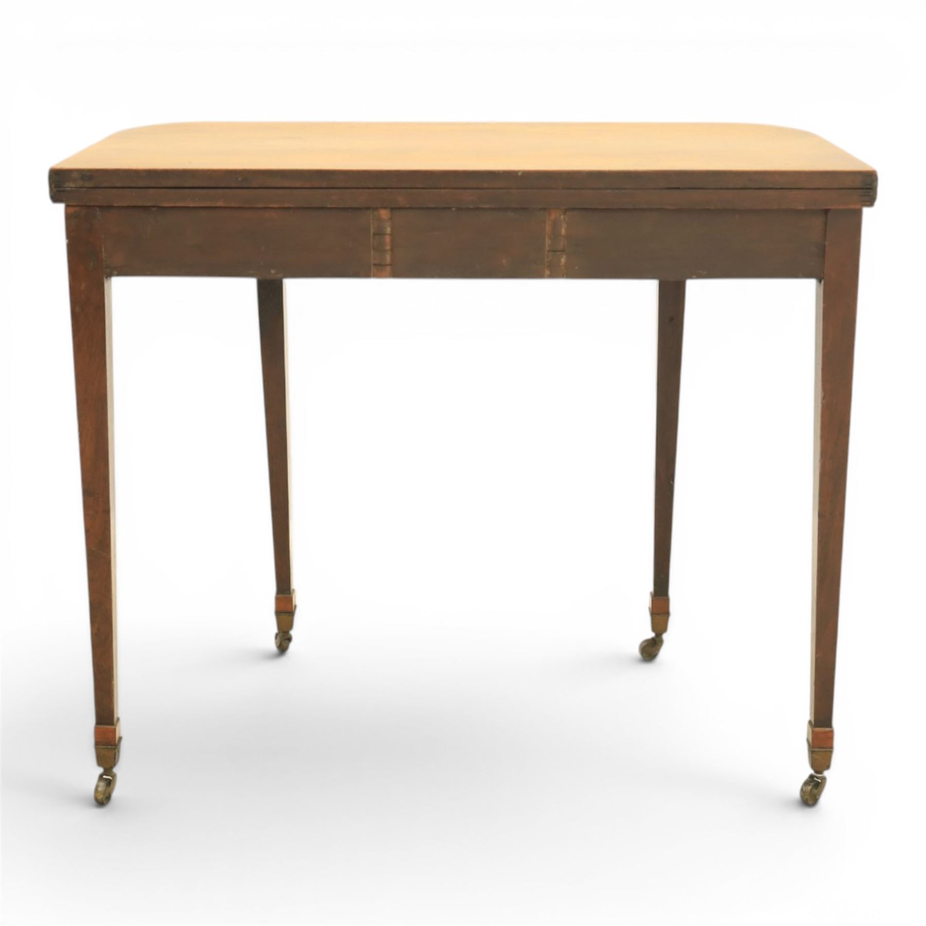 Regency mahogany fold-over tea table, rounded rectangular top with gateleg action, inlaid and crossbanded frieze, raised on squared tapering supports on brass castors