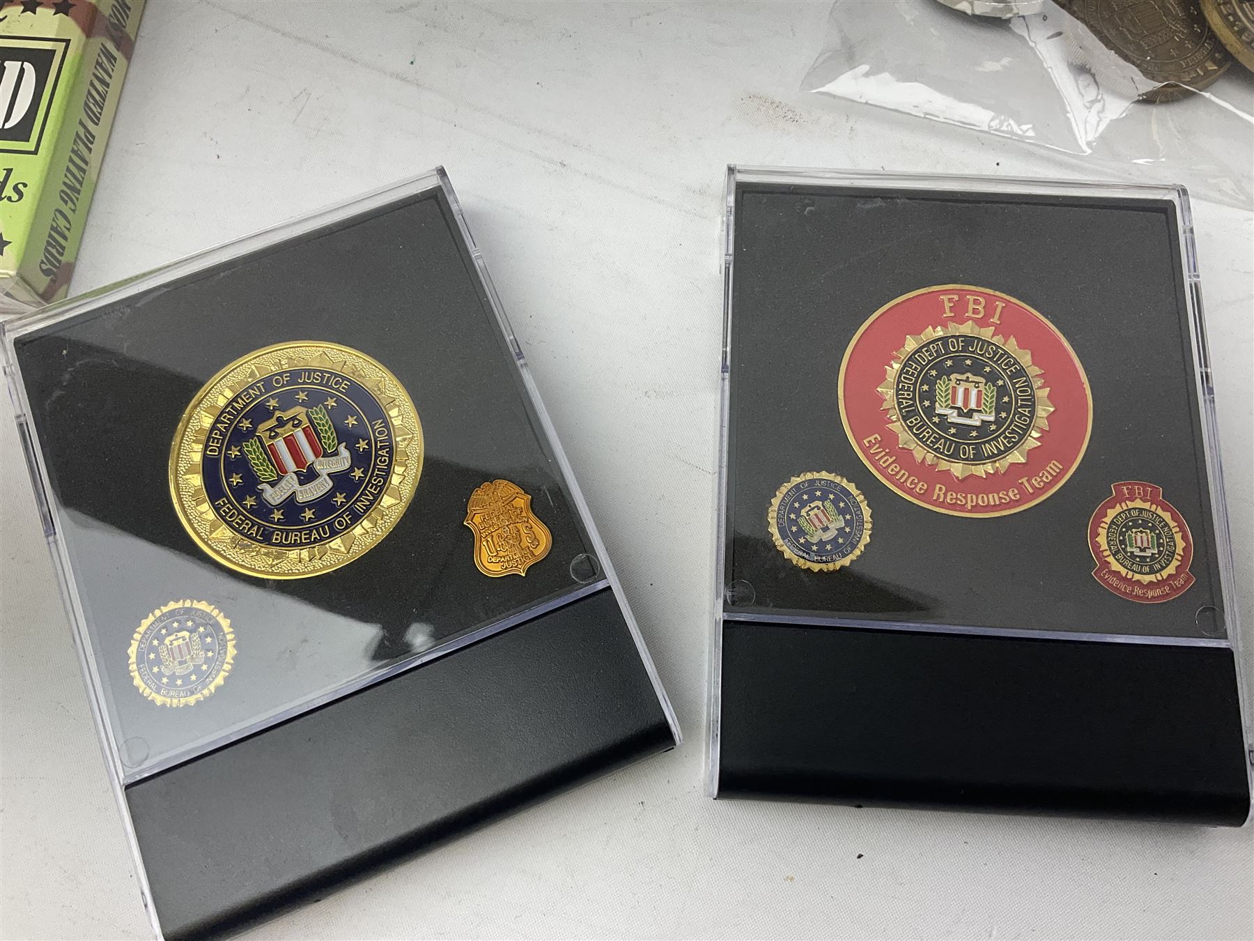 Sixty-nine American challenge coins of military and security force interest including FBI, OSI, IRS, Customs, Iraq War etc, two in easel display cases; together with two unopened packs of playing cards for Iraqi Most Wanted and Radacad
