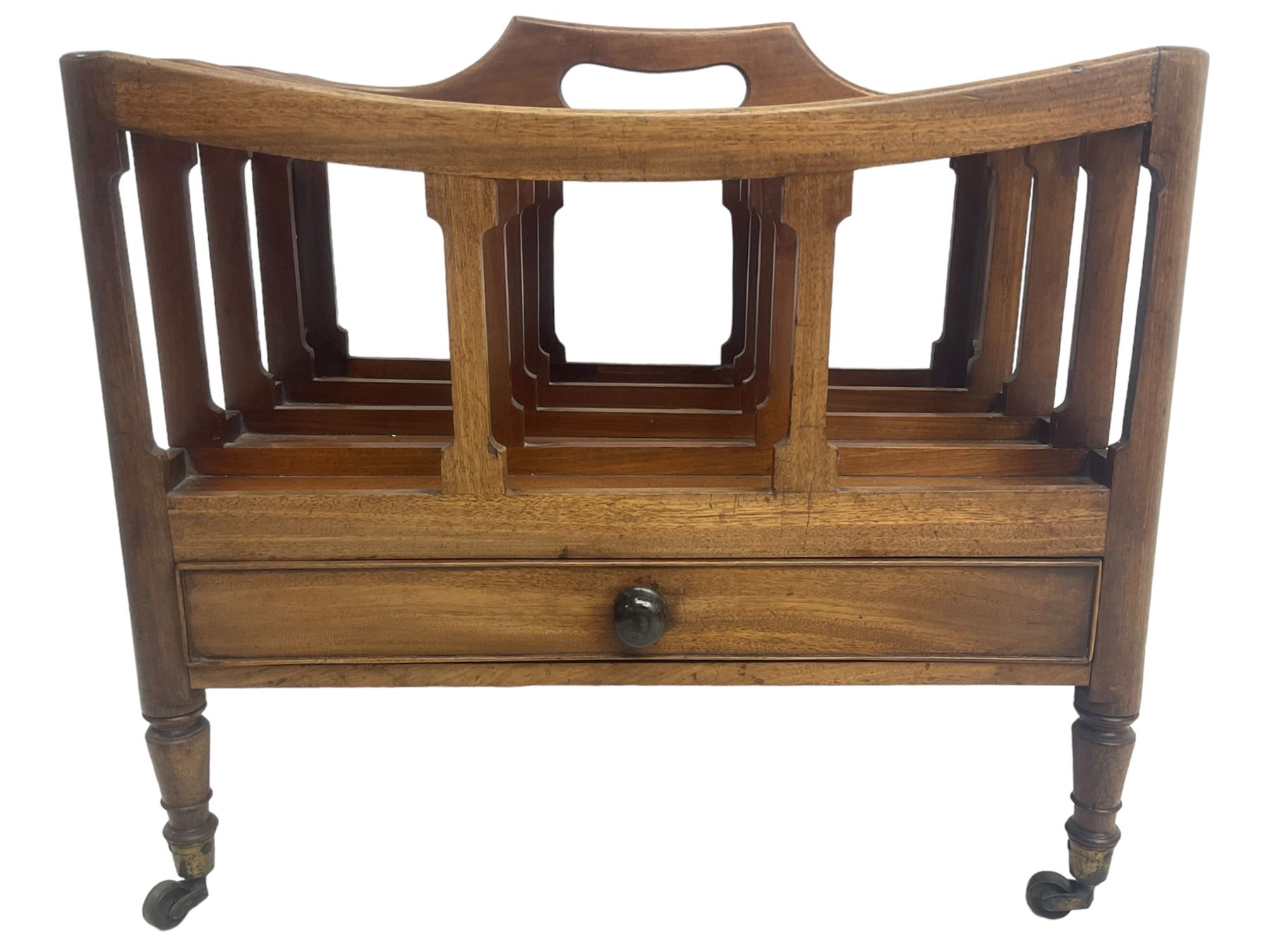 George III mahogany four-division Canterbury, the concave shaped dividers with a central pierced handle, over a single cock-beaded drawer, raised on turned supports terminating in brass cups and castors