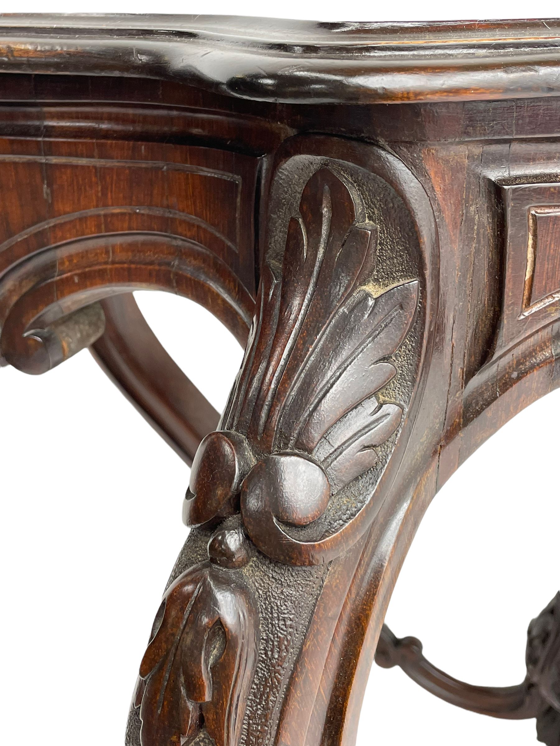 19th century Irish rosewood centre table, the shaped and moulded top over shaped apron carved with scrolled foliage, on serpentine supports carved with bell flowers, the supports united by anthemion carved finial and s-scroll x-framed stretchers