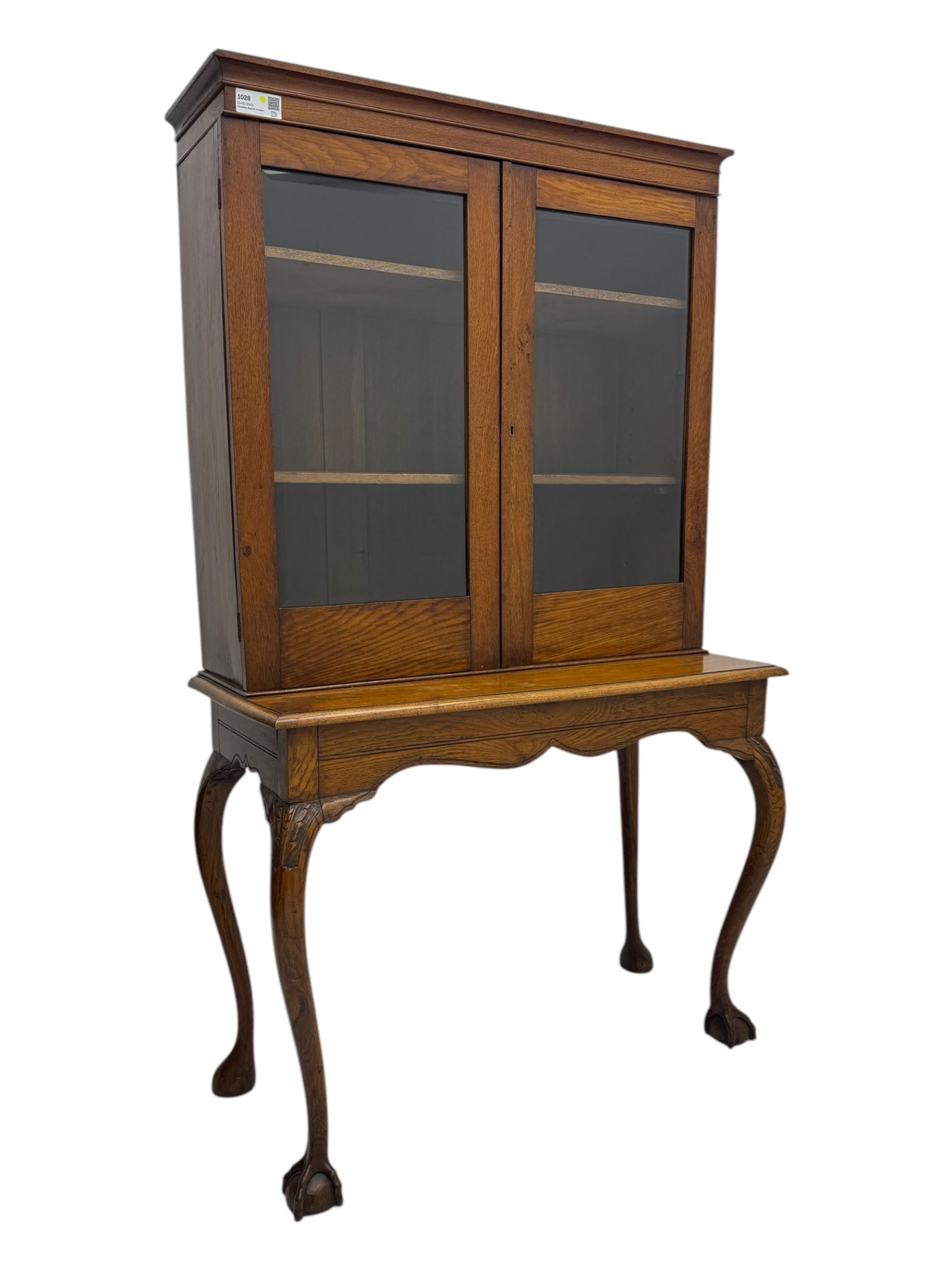 Late 19th century oak display cabinet, rectangular form with a pair of glazed doors enclosing shelves, raised on cabriole supports with carved detailing ending in claw feet